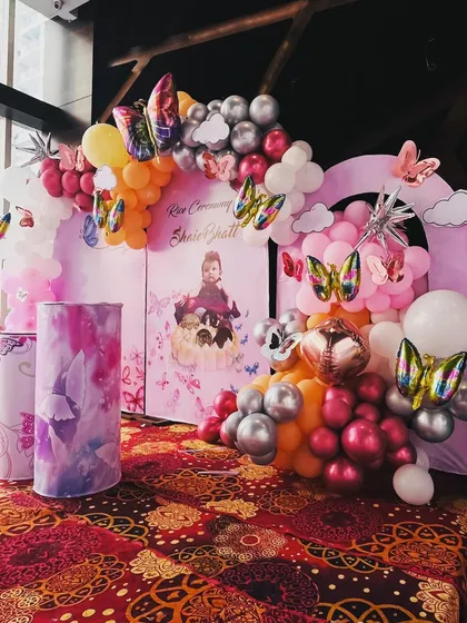The vibrant colors of the balloons and the personalized backdrop make this a wonderful setup for celebrating a baby's milestone.