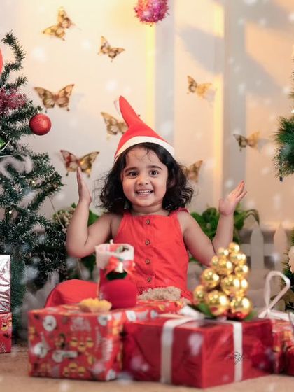 A full view of the Christmas studio setup, with a happy toddler surrounded by presents and festive decorations. I provide all the props you see here.