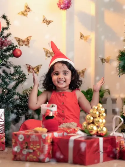 A full view of the Christmas studio setup, with a happy toddler surrounded by presents and festive decorations. I provide all the props you see here.