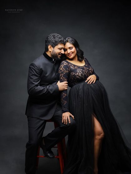 An intimate seated portrait of the couple. The black gown and suit create a formal, elegant look, while the pose feels warm and connected.