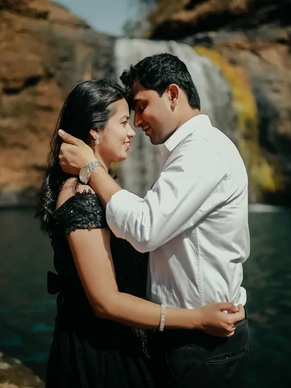 A tender moment captured in time. The groom gently holds her face as they share a loving look, with the waterfall creating a stunning background.
