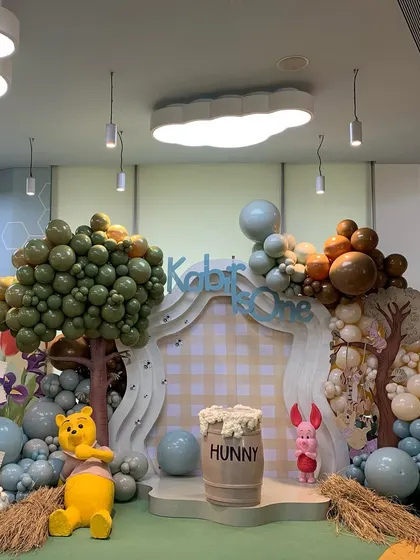 This wide shot captures the entire Winnie the Pooh themed area, designed to be a charming and immersive photo spot for the birthday boy and his guests.