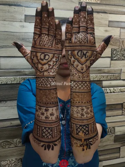 The bride proudly displays her full engagement mehndi, featuring initials, rings, and elephant processions on the forearms.