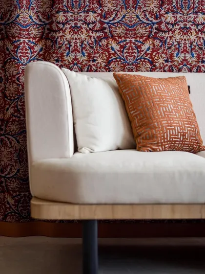 A close-up of the sofa, showing the beautiful texture of the fabric and the rich colors of the Kalamkari art piece in the background.
