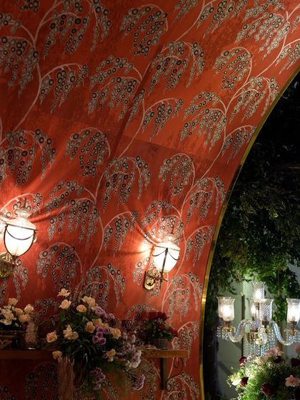 The entrance to this grand reception featured an arched tunnel lined with custom-printed fabric in a rich red hue, illuminated by vintage-style wall sconces for a dramatic effect.