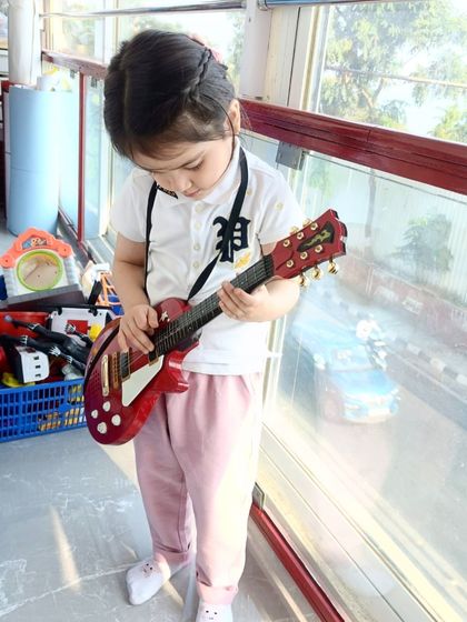 Focused on her "instrument," this student is lost in a world of imaginative play, a cornerstone of our teaching method.