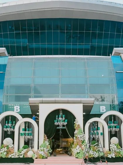 The grand entrance to the venue, framed by our custom-built white arches and emerald chandeliers, showcasing how we transform the exterior to match the interior's opulence.