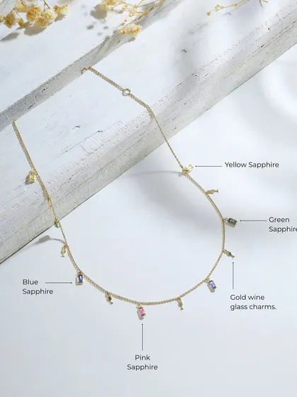 A detailed product shot of the multi-sapphire and wine glass charm necklace, labeling the different colored sapphires used in the design.