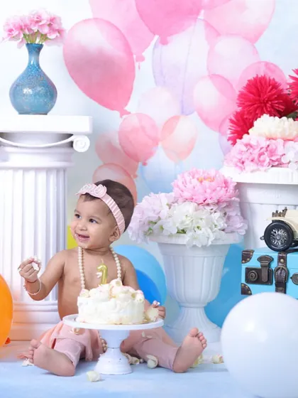 For a classic look, my studio cake smash sessions offer a controlled environment with elaborate backdrops. This setup features pastel balloons and floral arrangements for a soft, celebratory feel.
