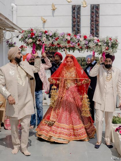The bride, Mehak, making her grand entrance under a floral canopy held by her brothers, a powerful and emotional moment.