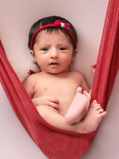 This awake shot in the red fabric hammock is so engaging. It's a great example of how we can capture your baby's personality and bright eyes.