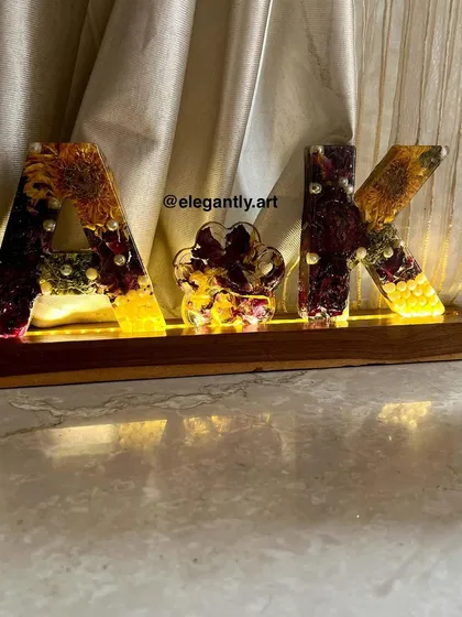 This monogram lamp, made with varmala flowers, is a beautiful way to celebrate a couple's union. The "AK" initials are filled with preserved flowers and a paw print, representing their whole family.