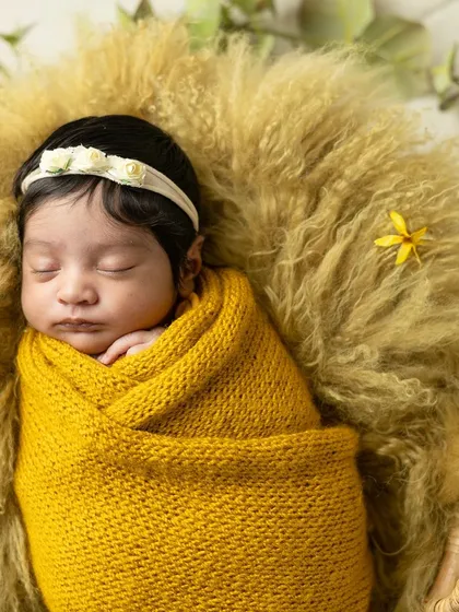 A peaceful newborn wrapped snugly in a yellow knit blanket, dreaming sweetly. I use soft textures and warm colors to create cozy and artistic newborn portraits.