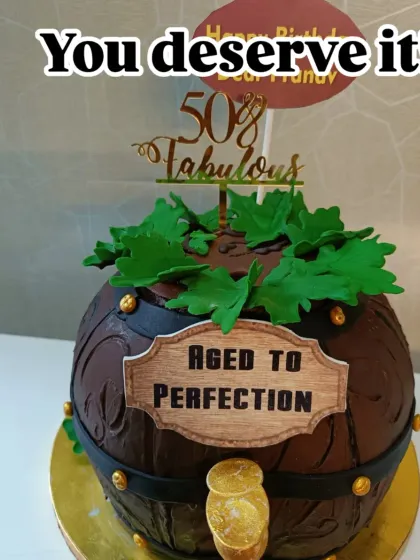 An "Aged to Perfection" wine barrel cake. This sculpted cake is perfect for a wine enthusiast's milestone birthday, complete with fondant grape leaves.