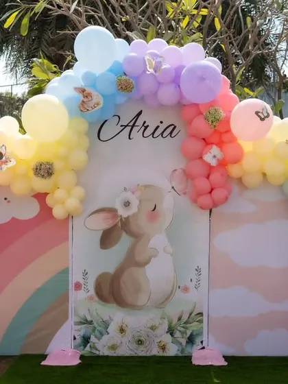 The main backdrop for Aria's rabbit-themed Mundan ceremony. A rainbow-colored balloon arch frames a central panel with a large, cute bunny illustration, creating a perfect photo spot.