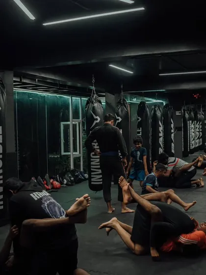 The gym floor is covered with students drilling various Jiu-Jitsu techniques during a packed class.