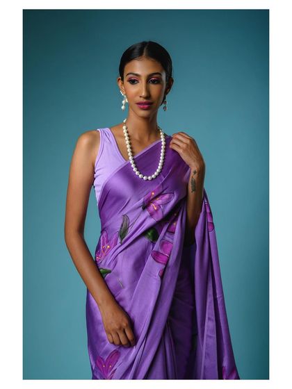 A close-up portrait that highlights the model's elegance and the beautiful color of the purple saree. This type of shot adds a personal, relatable touch to a product listing.