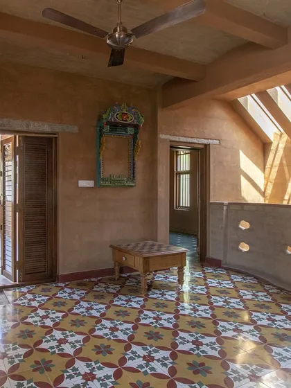 Sunlight streams from a skylight onto a floor of colorful, traditional Athangudi tiles, creating a vibrant and dynamic pattern.