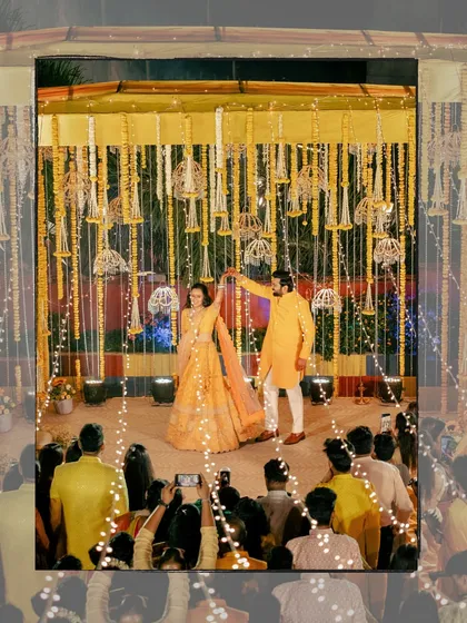 The couple's first dance at their sangeet, surrounded by guests and beautiful decor with fairy lights, creating a magical atmosphere.