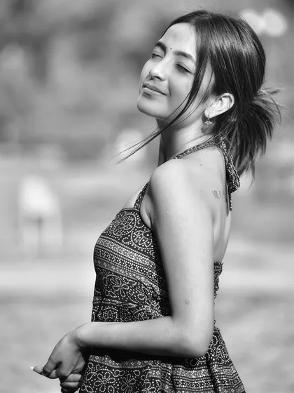 A serene black and white portrait, capturing a moment of quiet contemplation. The sunlight on her face and the gentle breeze in her hair create a beautiful, peaceful mood.
