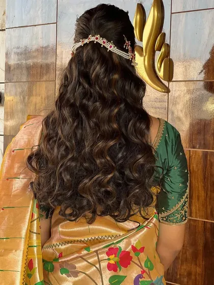 The back view of a modern bridal hairstyle with soft waves and a delicate hair accessory, perfect for a reception or engagement.