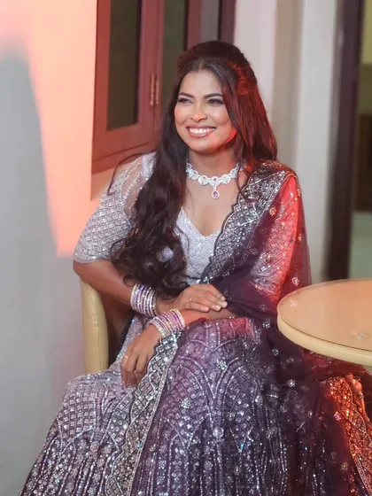 A happy bride in her sparkling reception lehenga. The makeup is glamorous and her smile lights up the room.