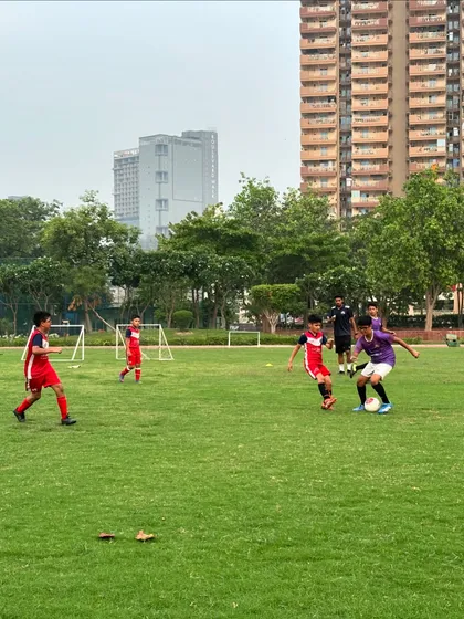 A player in our purple kit skillfully dribbling past a defender in red. This showcases the individual skill we nurture.