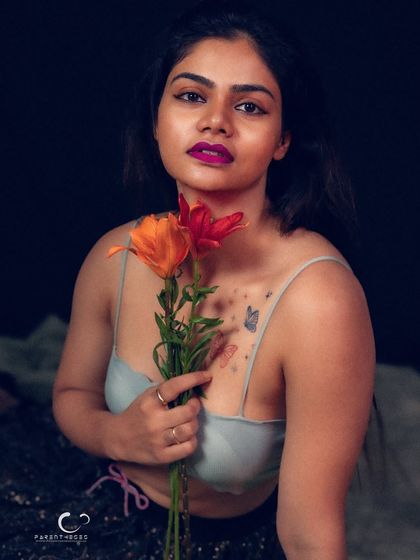 A bold and intimate portrait against a dark background. The vibrant flowers provide a beautiful contrast to her intense gaze and the moody lighting.