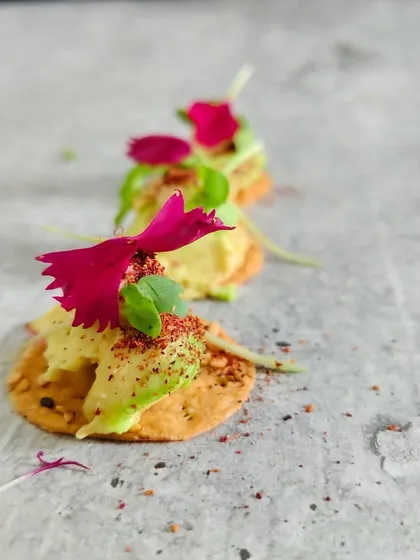 Delicate artistry on a crisp base. Creamy avocado spheres meet the freshness of microgreens, kissed with edible petals and a hint of spice for an elegant bite.