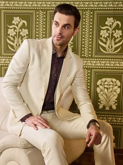A seated portrait in the ivory linen suit. The lightweight fabric drapes beautifully, ensuring comfort and style for any daytime event or summer gathering.