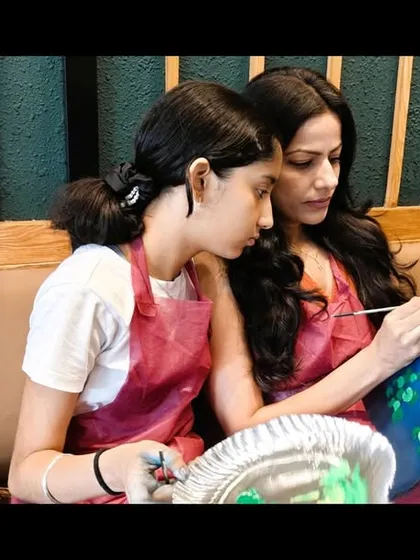 A mother and daughter sharing a quiet moment of collaboration during the Water Lilies workshop. Painting together is a beautiful way to bond.