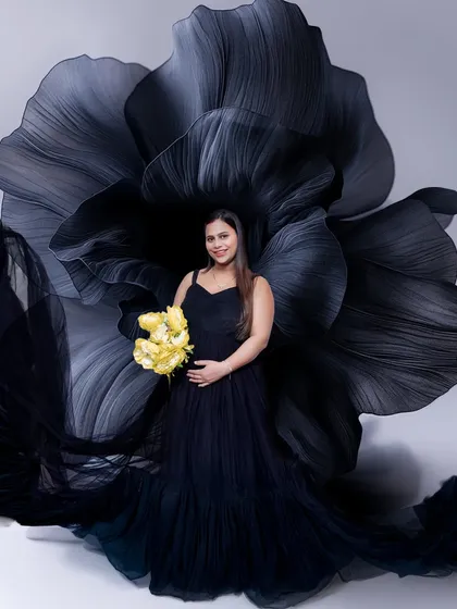 A closer look at this elegant setup. The contrast between the dark, dramatic gown and the bright yellow bouquet creates a stunning focal point in this pregnancy portrait.