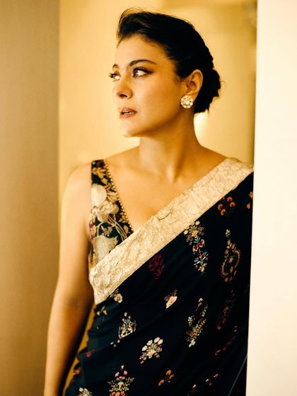 The warm lighting enhances the rich colors of the embroidery on this beautiful black saree, creating a regal and sophisticated look.