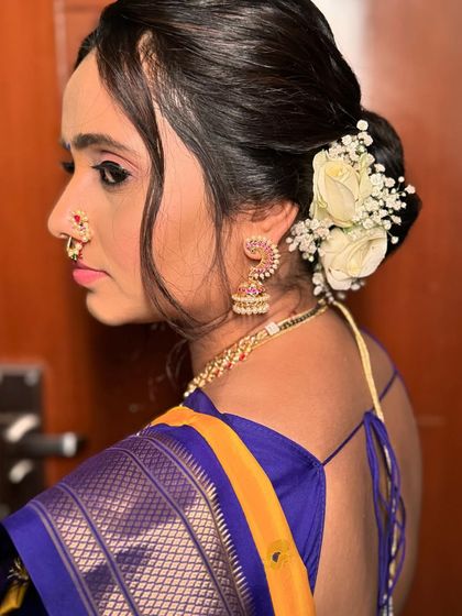The bride's side profile highlights her traditional 'nath' and the soft floral details of her hair. This is a beautiful example of a complete Maharashtrian bridal look.