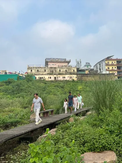 This is the result of our collective effort. A family enjoys a walk across a restored bridge at Ghata Bundh, a space we reclaimed from neglect. We create living, breathing public spaces where communities can reconnect with nature.
