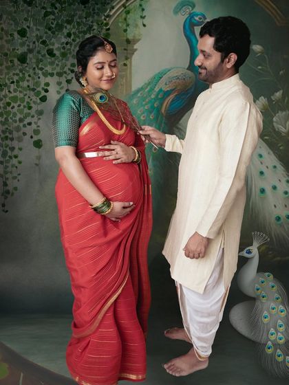 A playful and loving interaction between the couple, set against a beautiful peacock backdrop. These are the candid moments that make a traditional maternity photoshoot so special.