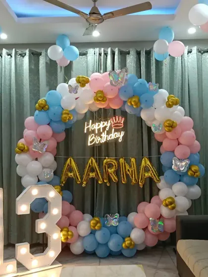 A 13th birthday home decoration with a balloon ring in pink, blue, and gold, plus a large "13" marquee number.
