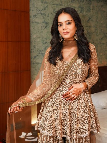 A full-length view of the outfit. The warm, bronze tones of the makeup perfectly complement the golden embroidery of her attire.