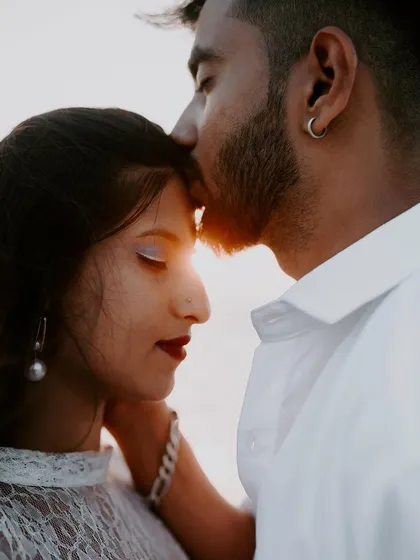 A close-up, tender moment between a couple during their sunset beach photoshoot. Capturing these gentle interactions is key to our storytelling style.
