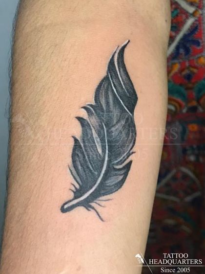 A feather tattoo on the forearm, a classic symbol of freedom, spirituality, and travel.