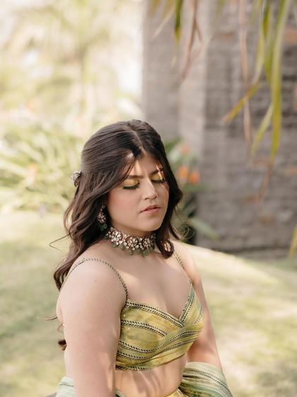 A serene moment for the bride before her Haldi ceremony. Her makeup is soft and glowing, with beautiful wavy hair that complements her modern lehenga.