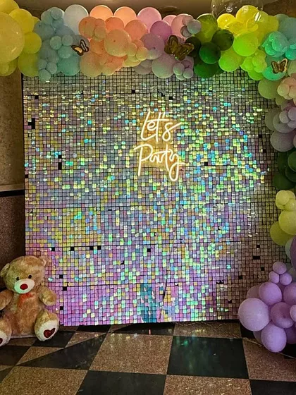 A shimmering photo booth corner for the "Wild Two" party, featuring a "Let's Party" neon sign against a sequin wall, a light-up number '2', and a friendly teddy bear.