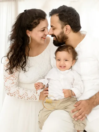 An intimate family moment, with parents smiling and touching noses while holding their baby boy.