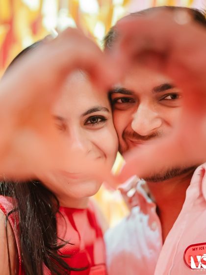 A close-up shot of a couple making a heart with their hands. This intimate and sweet gesture, captured in a colorful setting, is a beautiful symbol of their love.