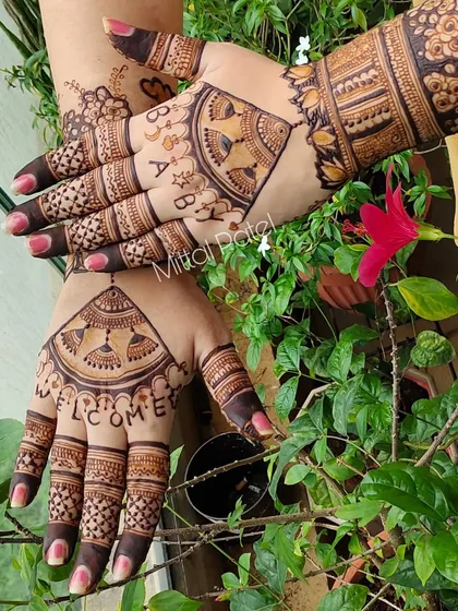 A creative baby shower design where the hands come together to spell "WELCOME BABY". The design is accented with traditional jhumka motifs.