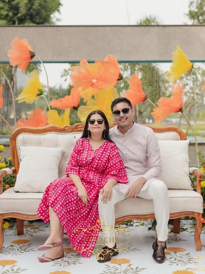 The couple poses for a photo on their beautifully decorated stage, surrounded by whimsical organza flowers.