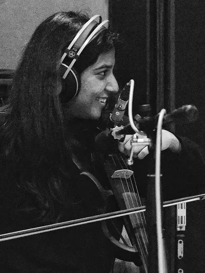 A black and white photo of Apoorva Krishna on the violin during rehearsal. Her melodic lines are a key voice in the ensemble.