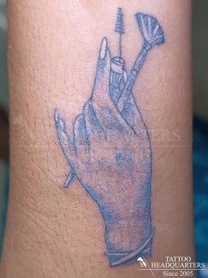 A unique tattoo for a makeup artist, featuring a hand gracefully holding makeup brushes.