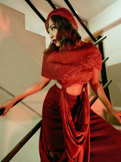 The crimson two-piece set, a statement that is both powerful and poised, captured on a staircase.