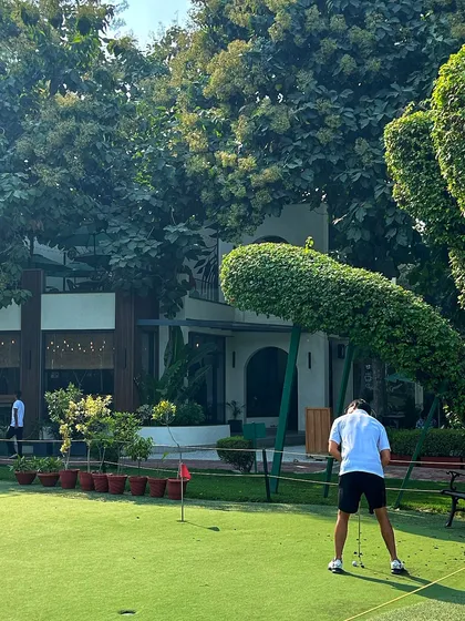 A golfer practices his putting in front of the uniquely shaped topiary and our clubhouse.
